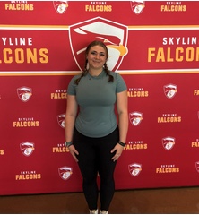 Una joven delante de una pancarta roja con el logotipo y el texto de los Skyline Falcons.